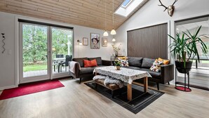 Een moderne woonkamer met een grote schuifdeur die uitkomt op een terras, een houten plafond en een dakraam.