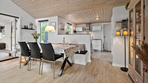 Een moderne keuken met houten kastjes, een zithoek met een tafel en stoelen, en uitzicht op de omgeving.