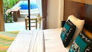 A hotel room with a bed, a view of an outdoor pool, and a ceiling fan. - Tropical Garden Inn (Penida Island)