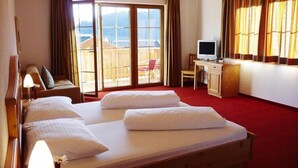 Habitación de hotel con dos camas, un escritorio, televisión y un balcón con vistas.
