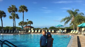 A swimming pool with lounge chairs and palm trees. - Sunset beach getaway (Treasure Island)