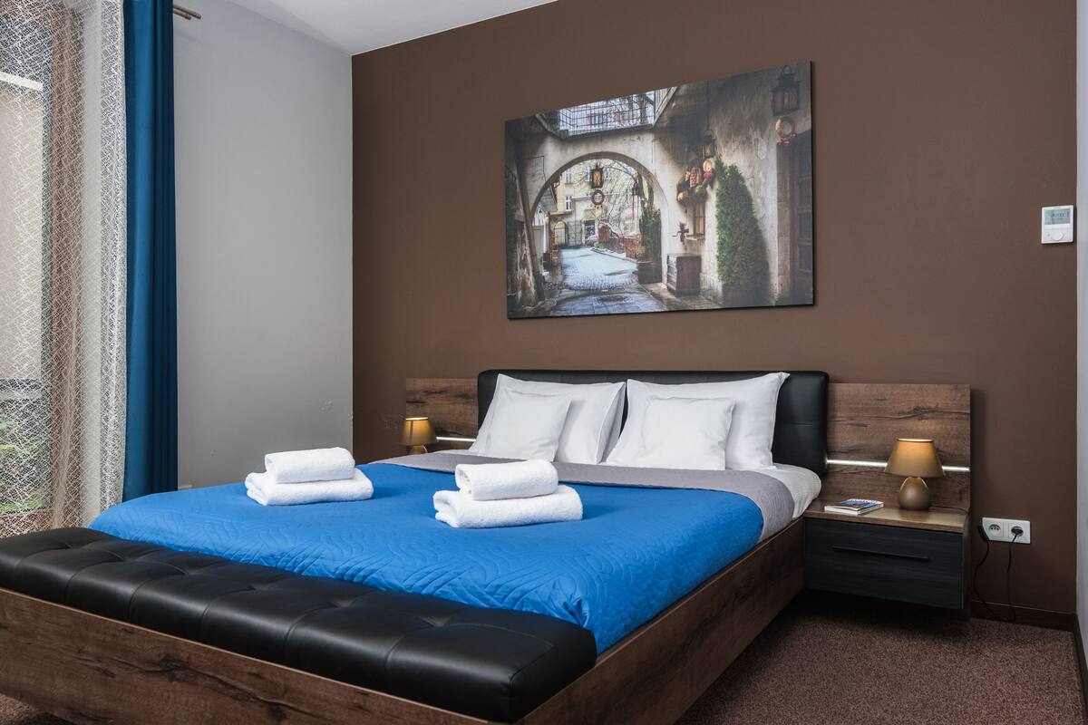 A neatly made bed with blue bedding, two white pillows, and folded towels.