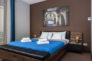 A neatly made bed with blue bedding, two white pillows, and folded towels. - goodhome Browar Lubicz (Kraków)