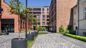 A paved walkway with planters and a brick building with multiple windows. - goodhome Browar Lubicz (Kraków)