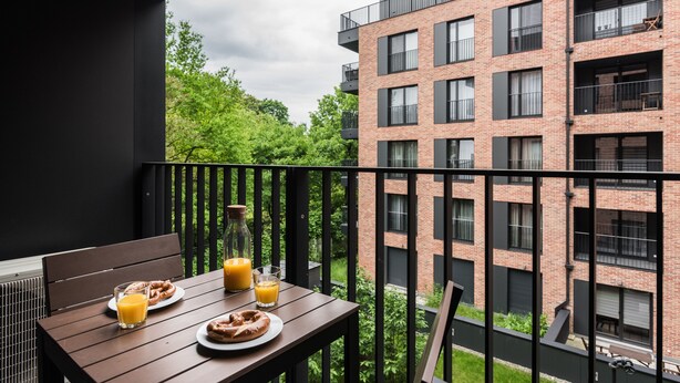 A balcony with breakfast items, a bottle, and a glass of orange juice. - goodhome Browar Lubicz (Kraków)
