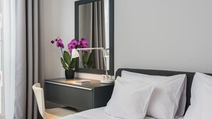A modern hotel room with a bed, a desk, a chair, a potted orchid, and a mirror. - goodhome Browar Lubicz (Kraków)