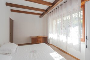 A bedroom with a bed, a desk, and a chair.