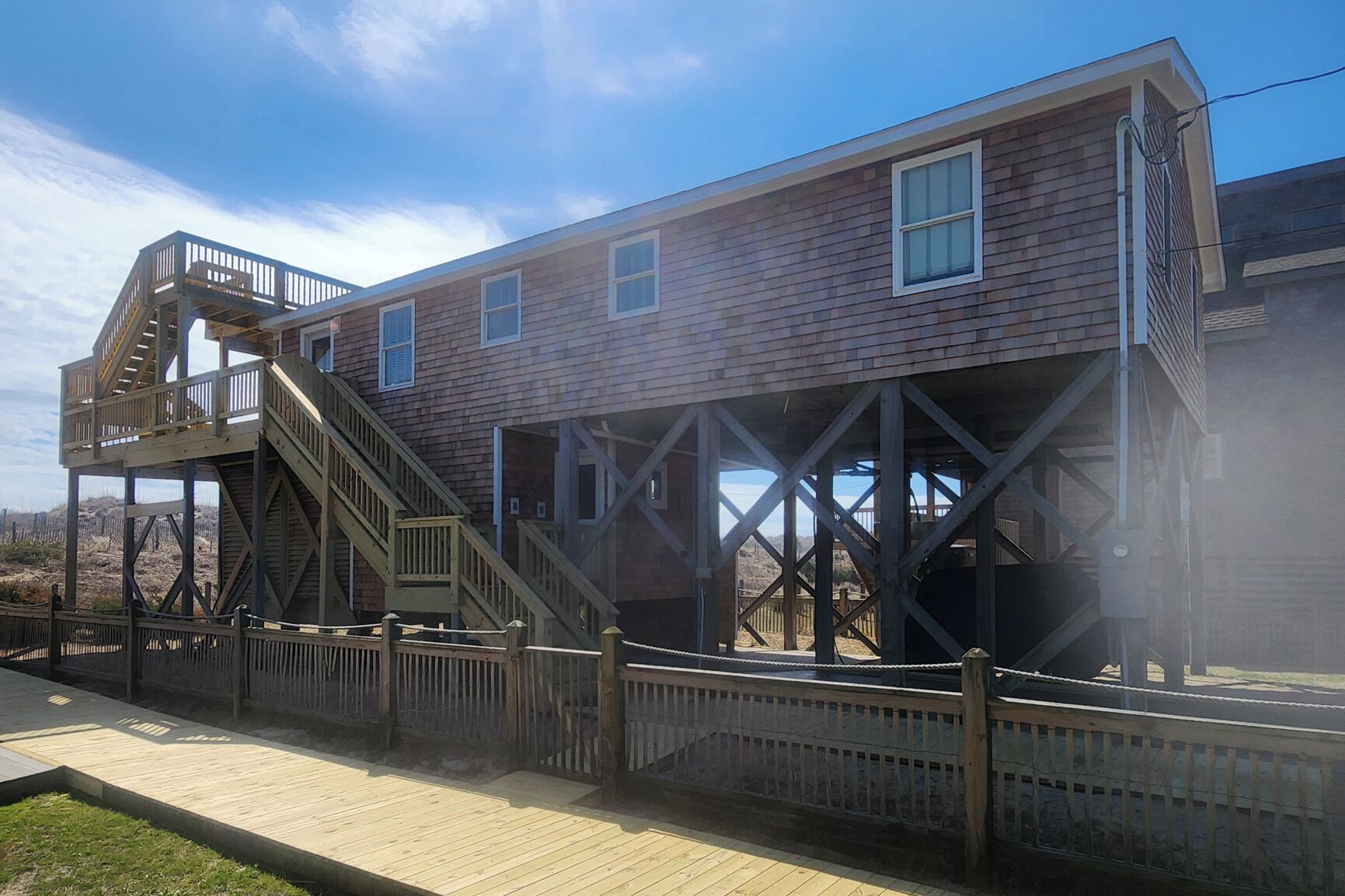 A two-story wooden building with a wooden deck and stairs leading to an upper level.