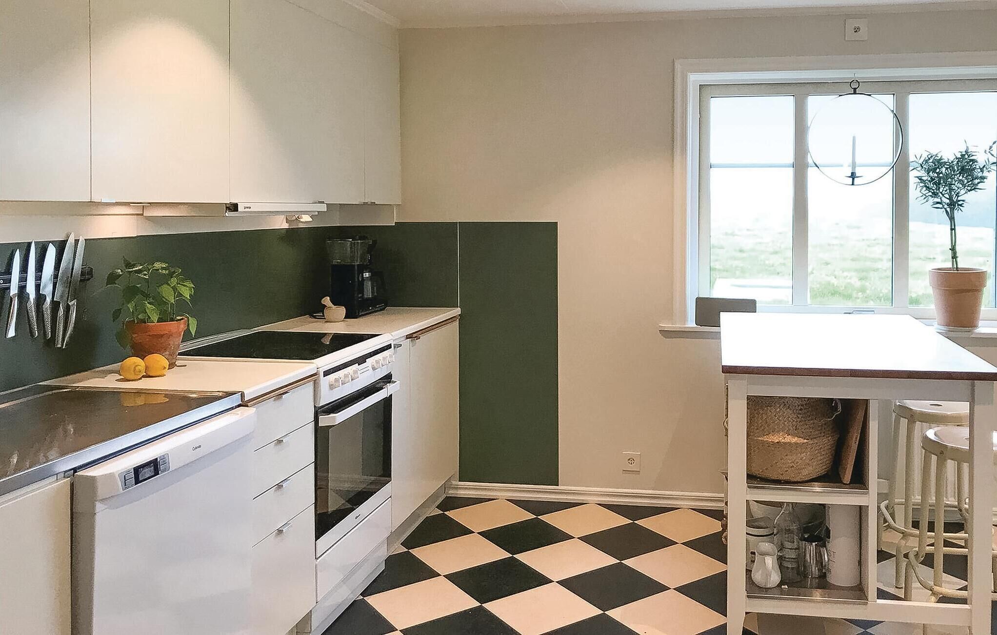 Une cuisine avec un sol à carreaux noirs et blancs, une machine à café et une plante en pot.