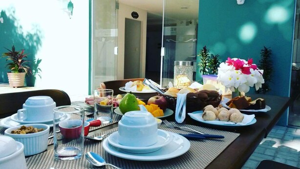 A breakfast setup with various dishes and drinks on a table outside a building. - Scenarium Hotel (Jaboatão dos Guararapes)