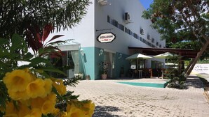 A building with a sign reading "SCENARIUM." There is a pool area with umbrellas and tables. - Scenarium Hotel (Jaboatão dos Guararapes)
