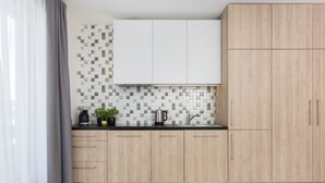 Uma cozinha moderna com armários de madeira clara, bancada preta e painel de fundo estampado.