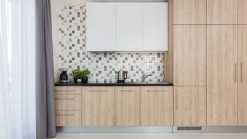 Uma cozinha moderna com armários de madeira clara, bancada preta e painel de fundo estampado.