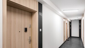 Um corredor moderno com portas de madeira, detalhes verticais em preto e números nas portas.