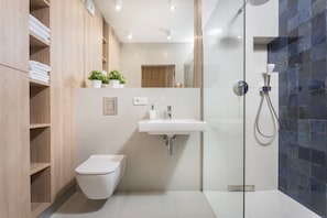 A modern bathroom with a toilet, sink, and shower.