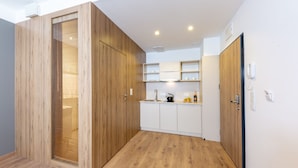 A modern kitchen with wooden cabinetry, white countertops, and a built-in oven. - Micro Apartments Kazou Residence (Warsaw)