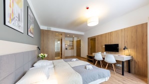 A modern hotel room with a bed, desk, and TV. - Micro Apartments Kazou Residence (Warsaw)