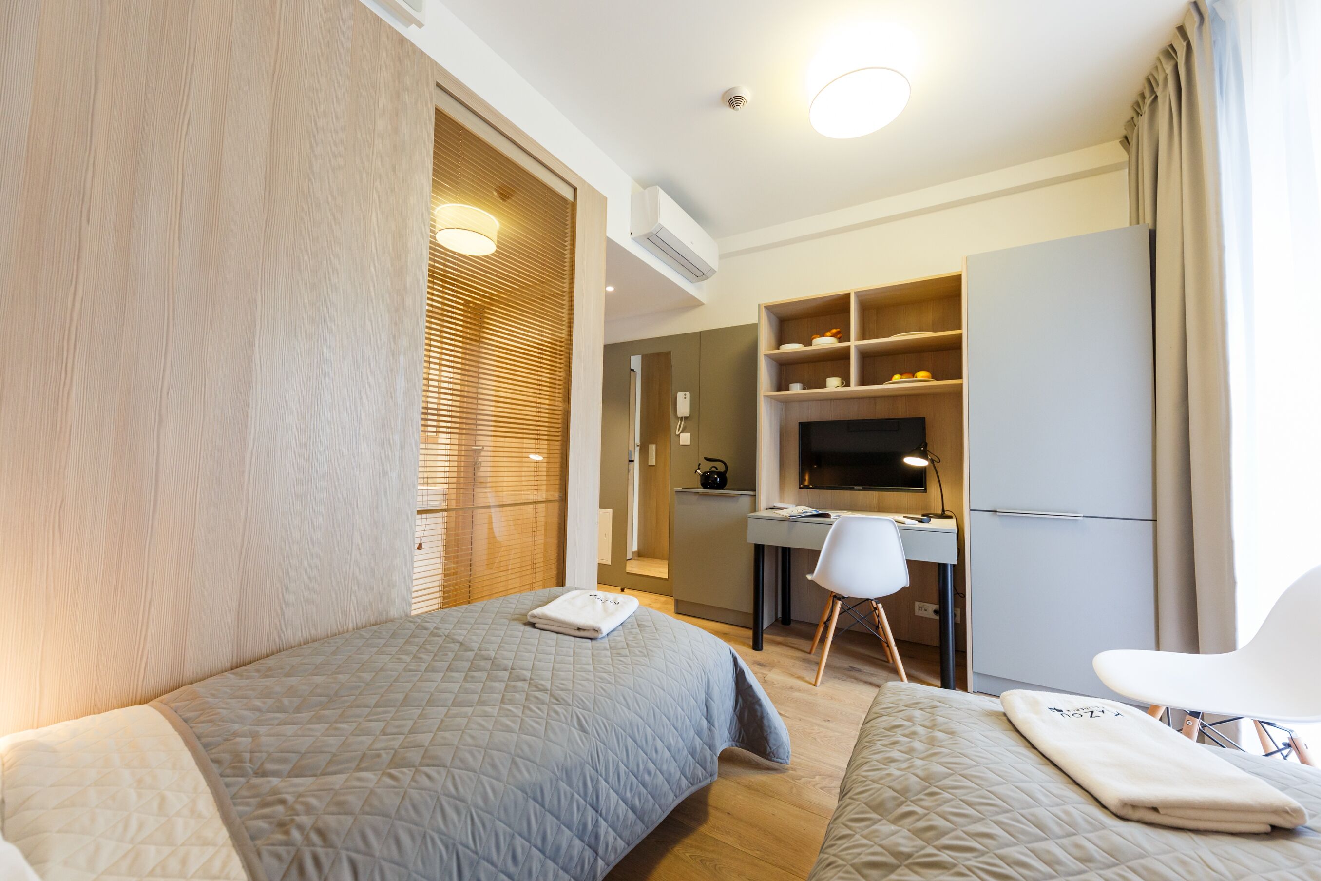 Una habitación de hotel con dos camas, un escritorio, una silla y un televisor.