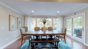 A dining room with a large wooden table, four chairs, a vase, and a blue patterned rug. - Beautiful home on the 11-mile lagoon system with a large private pool! (Hilton Head)