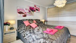 A modern bedroom with a large bed, decorative pillows, a bedside table with a lamp, and a wall-mounted artwork. - Villa Sonja is located directly on the sea (Medulin)