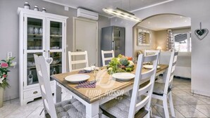 A dining area with a wooden table, white chairs, and a glass cabinet with dishes. - Villa Sonja is located directly on the sea (Medulin)