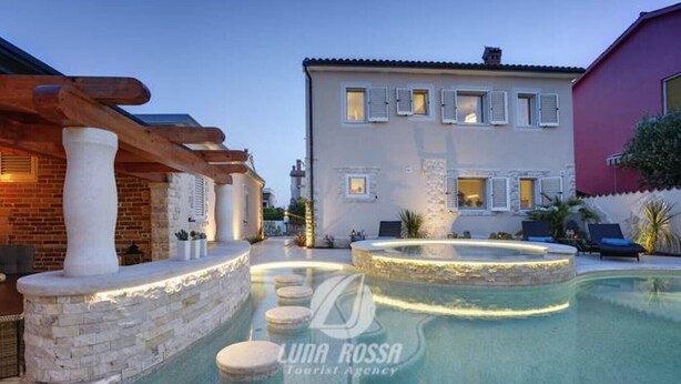 A pool area with stone steps and a lounge chair, surrounded by a building with multiple windows and a red facade. - Villa Sonja is located directly on the sea (Medulin)