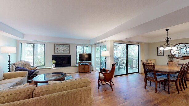 A spacious living room with a fireplace, a television, and a dining area with a table and chairs. - Fantastic Fazio Villa with Golf Course View! (Hilton Head)