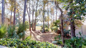 A residential property with a well-maintained garden, tall trees, and a clear view of the surrounding landscape. - Fantastic Fazio Villa with Golf Course View! (Hilton Head)