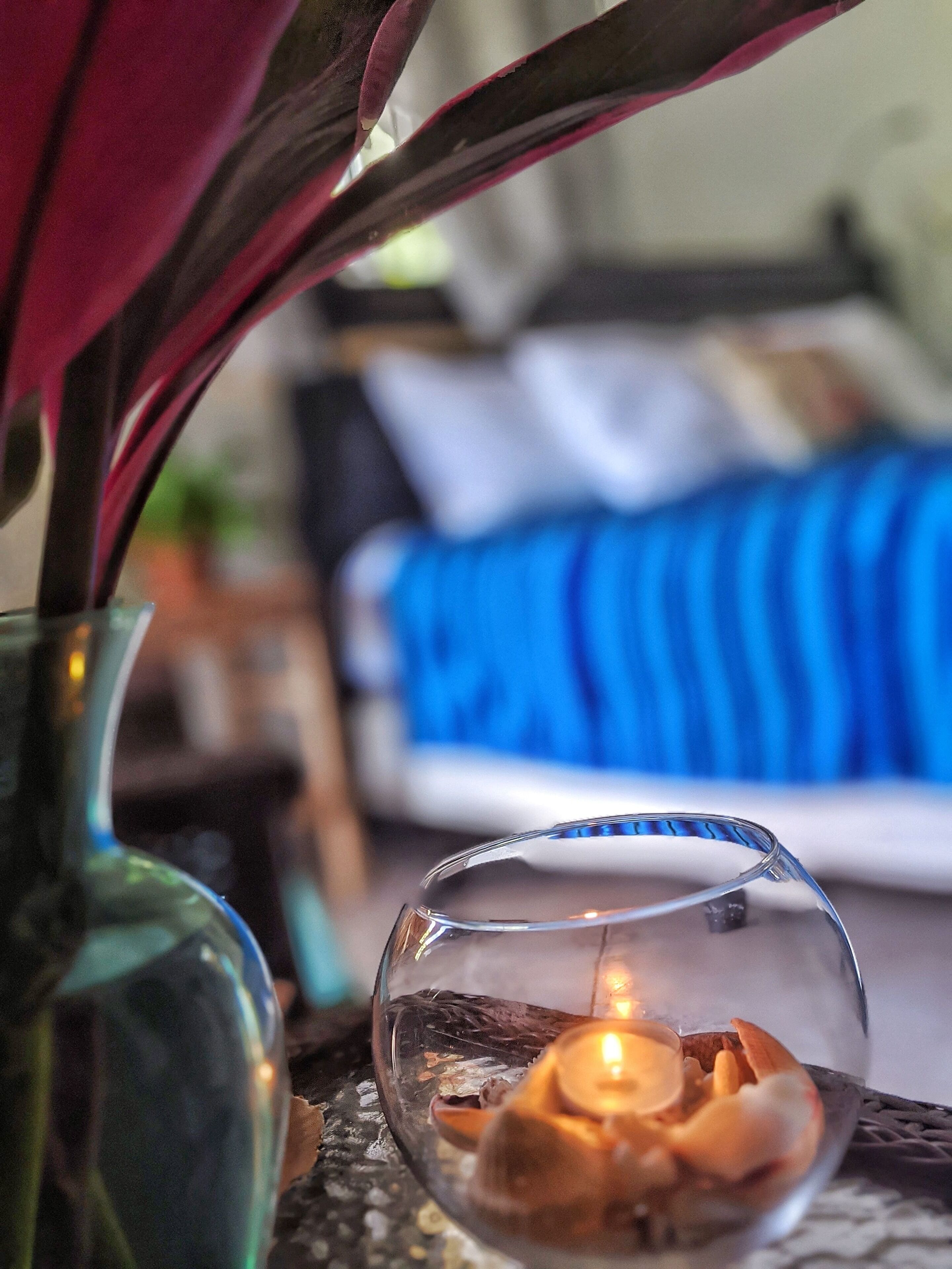 Un cuenco de vidrio transparente con una vela en su interior, sobre una superficie con textura.