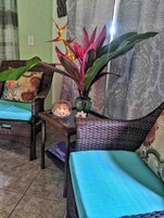 Una habitación con muebles de mimbre, una planta decorativa y una vela sobre una mesa.
