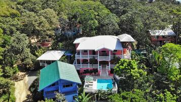 Una casa de varios pisos con balcón, rodeada de un bosque frondoso.