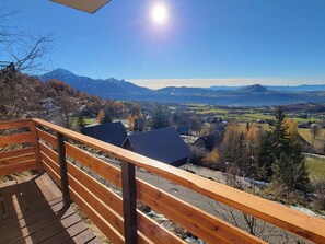 Una terraza de madera con vistas a un valle y montañas.