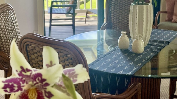 Een eetruimte met een glazen tafel, stoelen en uitzicht op de oceaan.