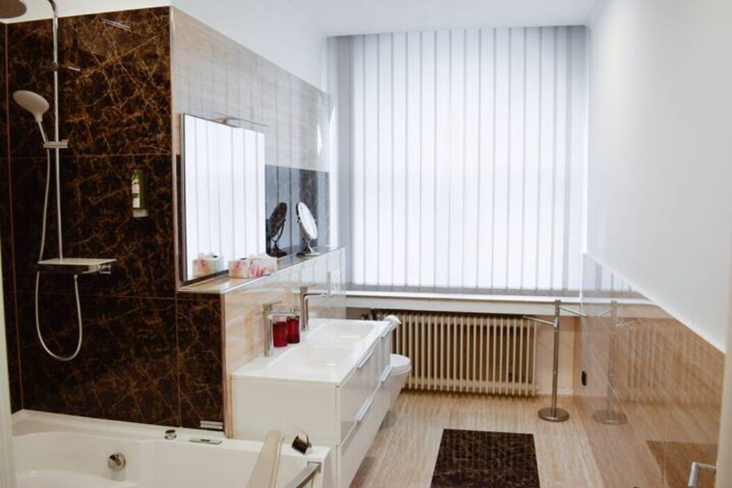 A modern bathroom with a bathtub, a shower, a vanity with a mirror, and a radiator.