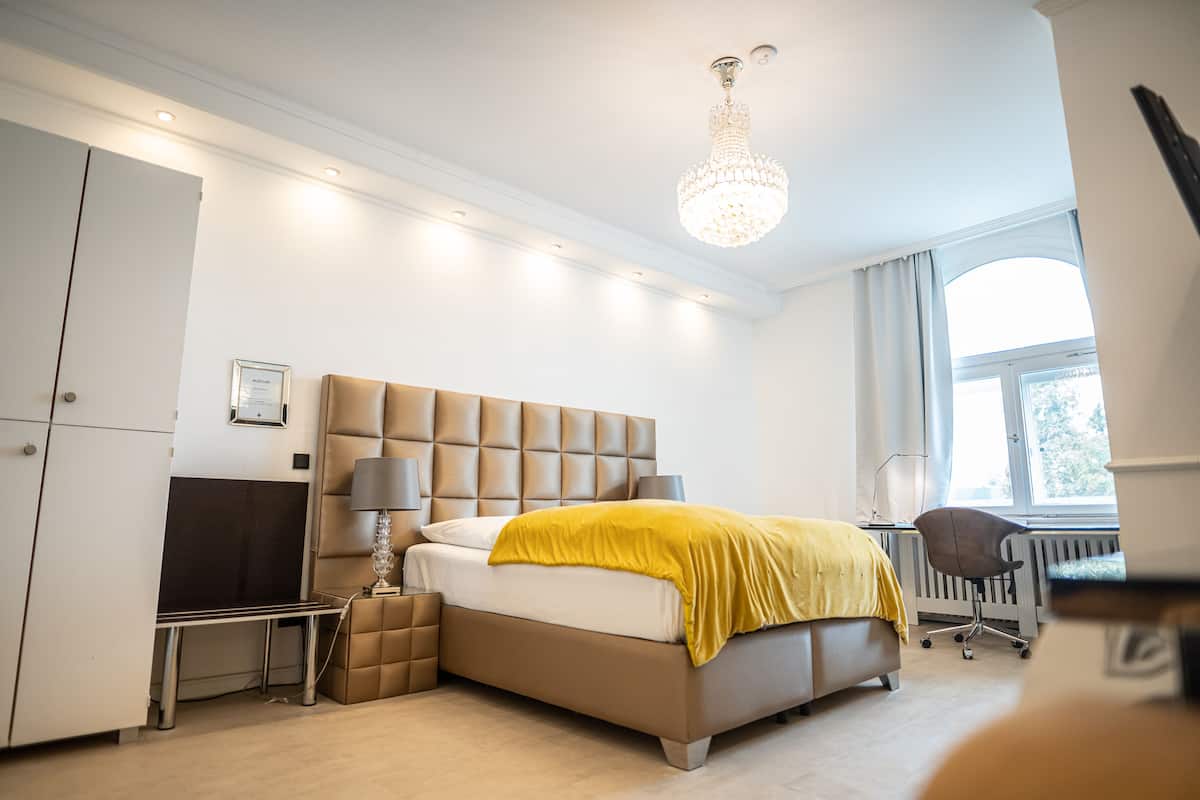 A modern bedroom with a large bed, a desk, and a chair.