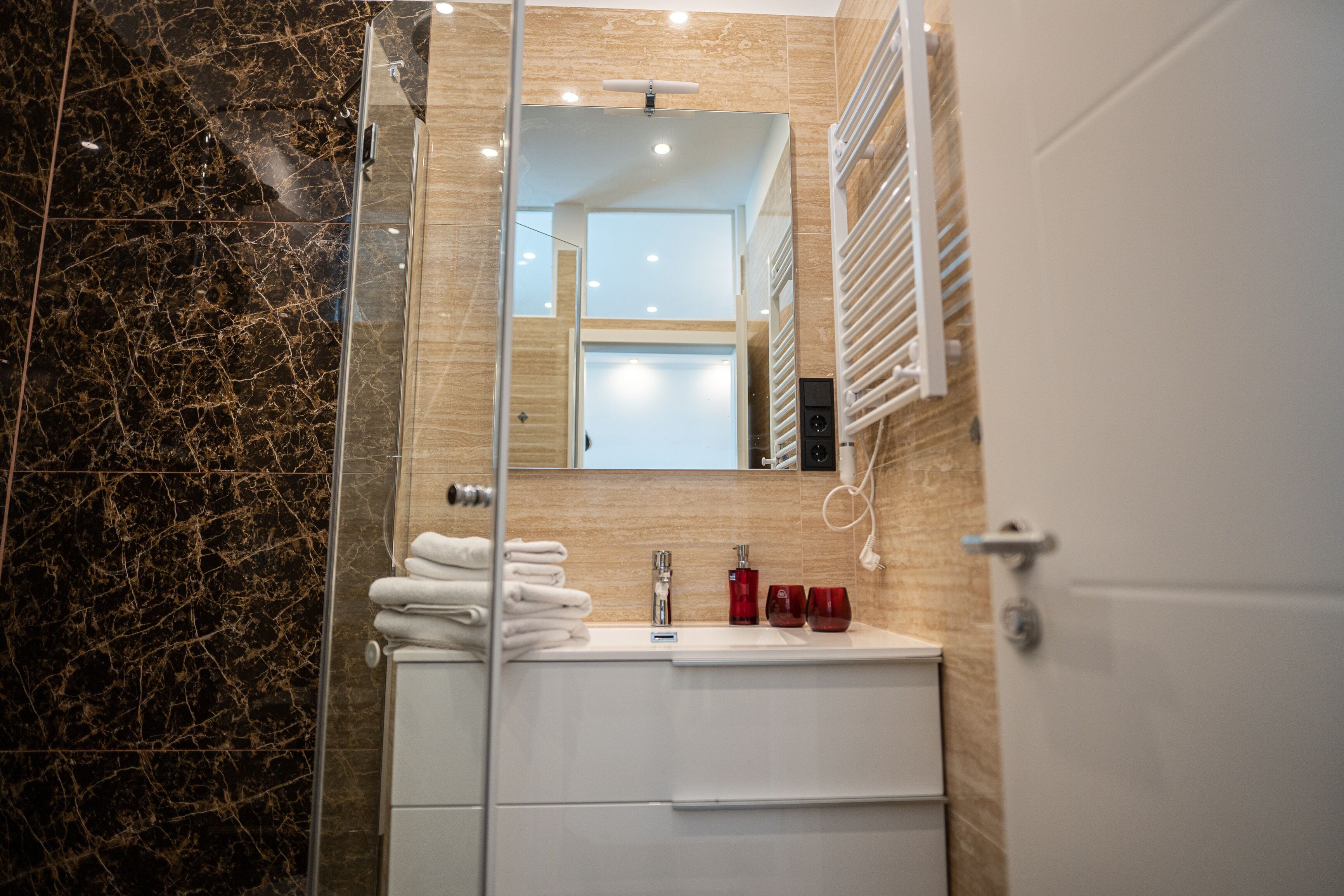 A modern bathroom with a glass shower enclosure, a white vanity, and a mirror.