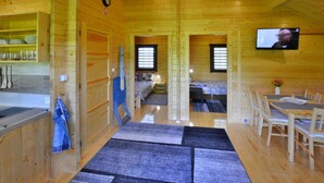 Ein Holzhütten-Interieur mit Küchenbereich, einem Esstisch und einem an der Wand befestigten Fernseher.