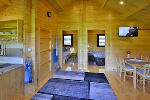 L’intérieur d’une cabane en bois comprend un coin cuisine, une table à manger et un téléviseur fixé au mur.