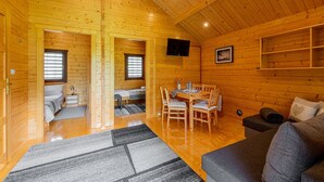 Ein Interieur einer Holzhütte mit Essbereich, einer Couch und einem Bett.