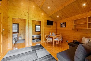 L'intérieur d'un chalet en bois comprend un coin repas, un canapé et un lit.