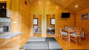 Ein Holzblockhaus-Interieur mit Küche, Essbereich und zwei Schlafzimmern.