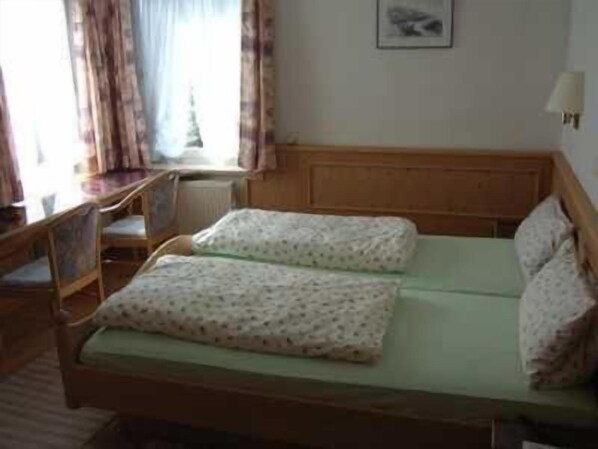 A single bed with a wooden headboard, a bedside table, and a chair. - Hotel Gasthof Stern (Mindelheim)