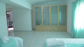 Un dormitorio con un armario grande, una cama y un baño visible a través de una puerta abierta.