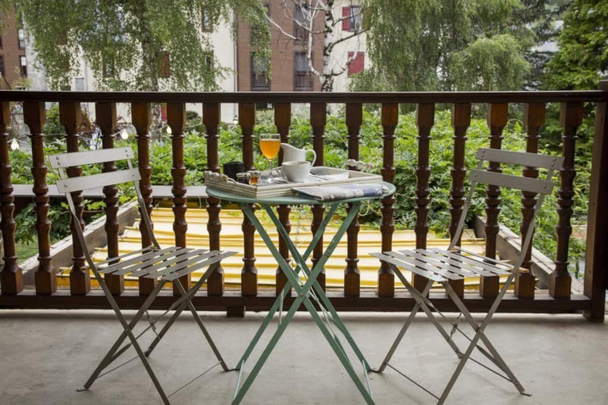 Ein Balkon mit Tisch für zwei Personen, ausgestattet mit einem Tablett, einem Glas Saft, einer Tasse und einem Buch.