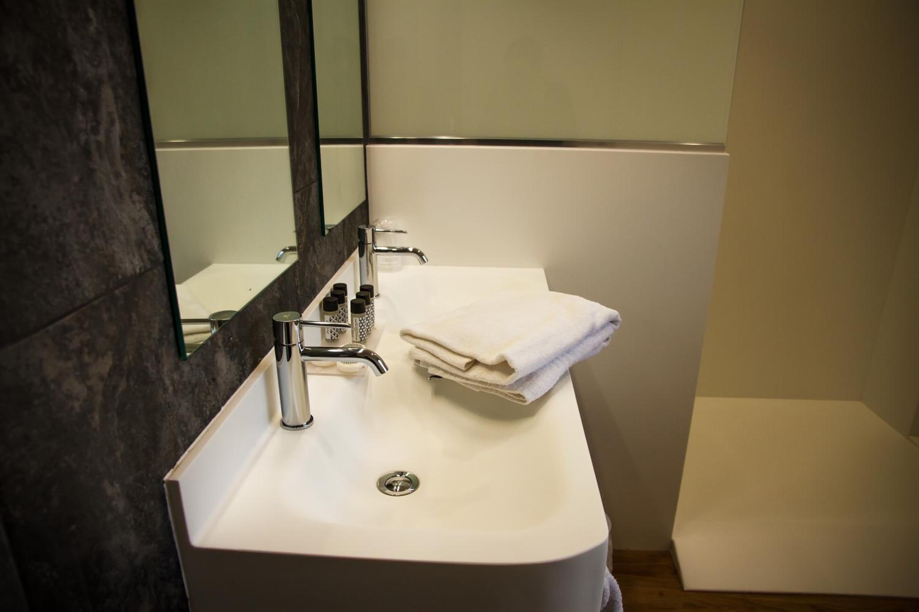A bathroom with a white sink, a mirror, and a towel.
