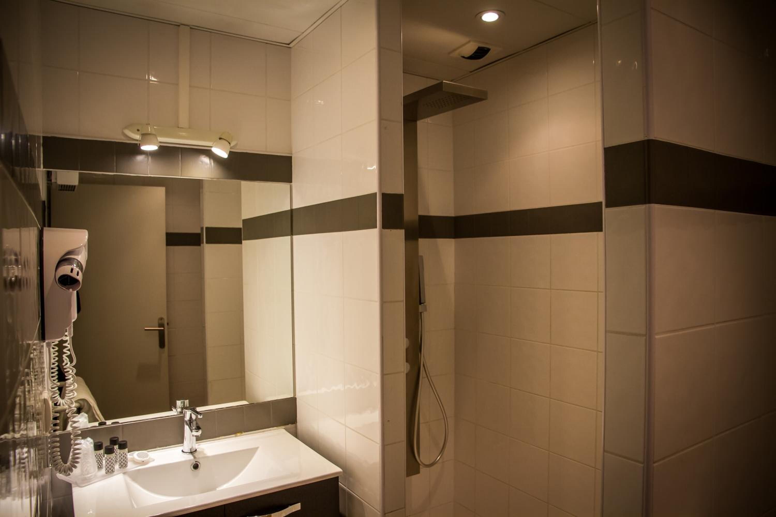 Een badkamer met een wastafel, spiegel en douche.