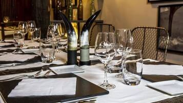 Una mesa de restaurante dispuesta con copas de vino, cubiertos y una carta.