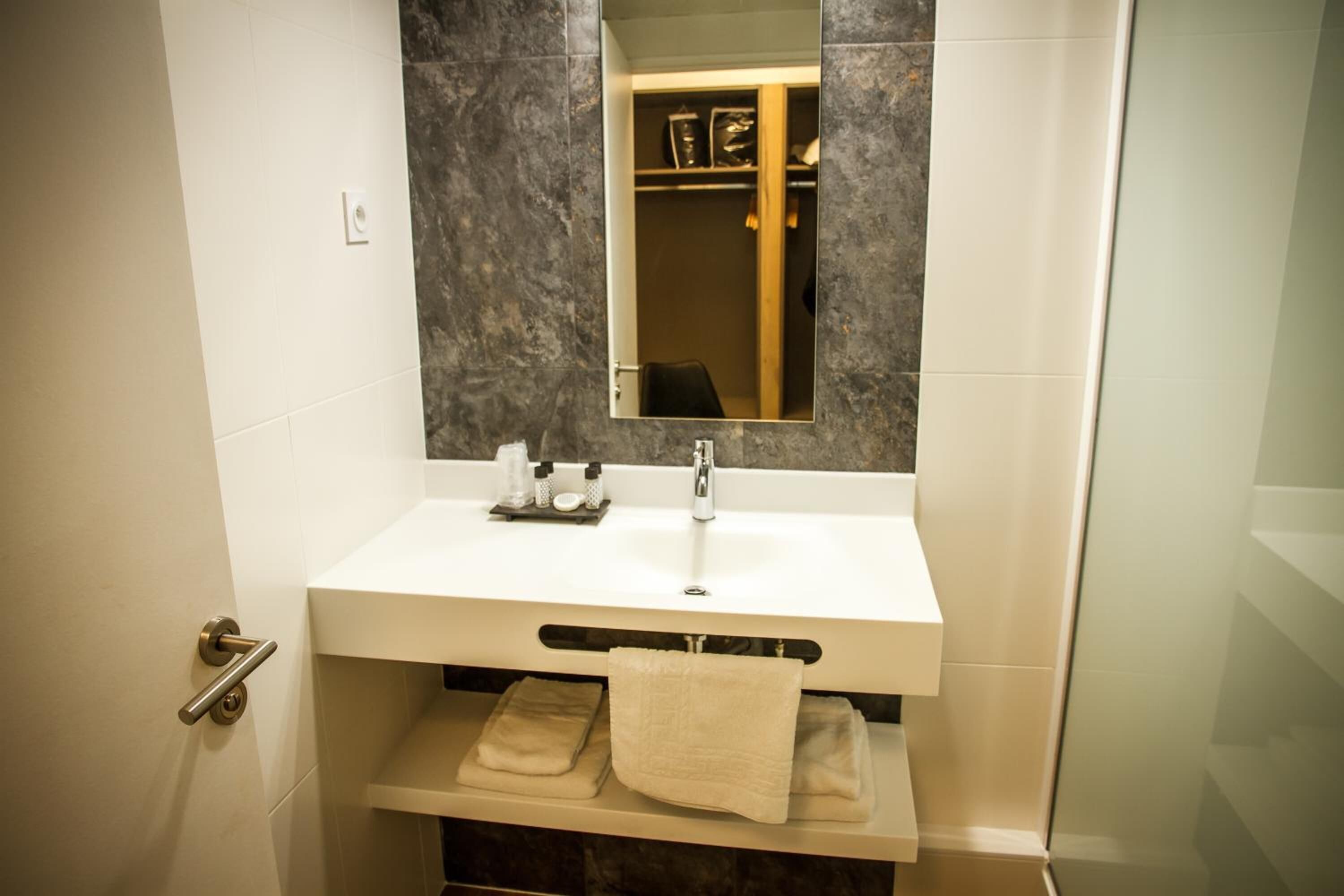 Une salle de bain avec un lavabo blanc, un miroir et un porte-serviettes.