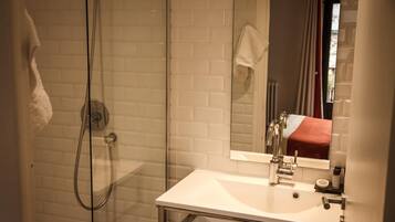 A modern bathroom with a glass-enclosed shower, a white sink, and a mirror above it.