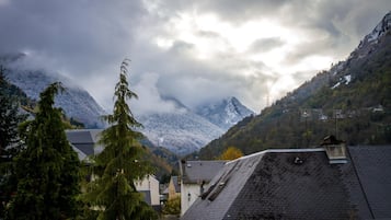 Paisatge montanyós amb pics nevats, un poble amb cases tradicionals i un cel nuvolós.